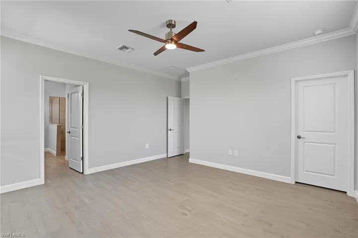 Unfurnished bedroom featuring ornamental molding, light wood-style floors, and a ceiling fan