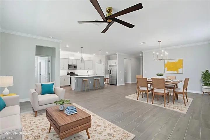 Living room with crown molding, ceiling fan, light wood-style flooring, and a chandelier