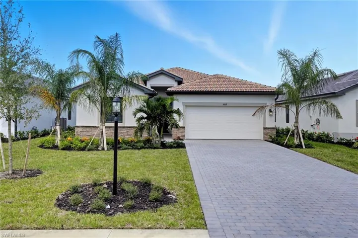 View of front of property featuring stone siding, stucco siding, a front lawn, decorative driveway, and an attached garage