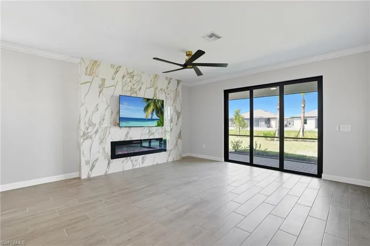 Unfurnished living room featuring crown molding, ceiling fan, a high end fireplace, and light wood-type flooring