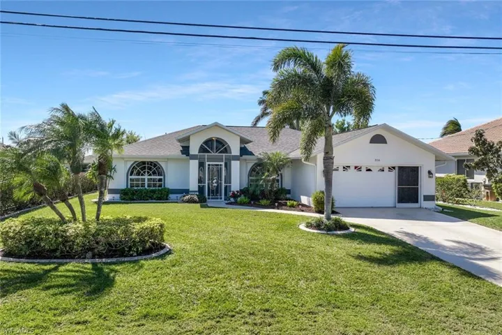 Ranch-style home featuring a front yard, a garage, driveway, and stucco siding