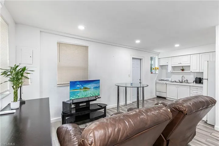 Unit C)Living area with light wood-style flooring and recessed lighting