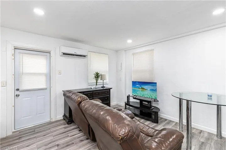 Unit C)Living room featuring light wood-style floors, recessed lighting, and a wall unit AC