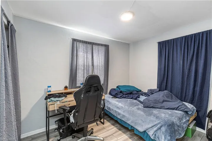 Unit A)Bedroom featuring wood finished floors and an office area