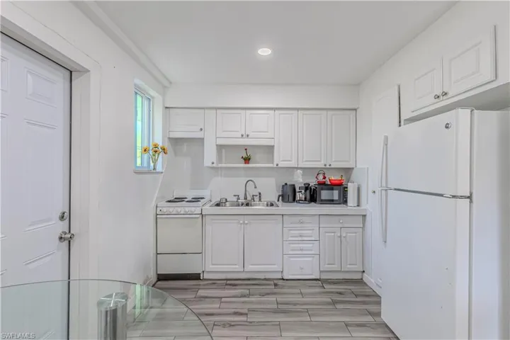 Unit C)Kitchen with white appliances, light countertops, white cabinetry, wood finish floors, and open shelves