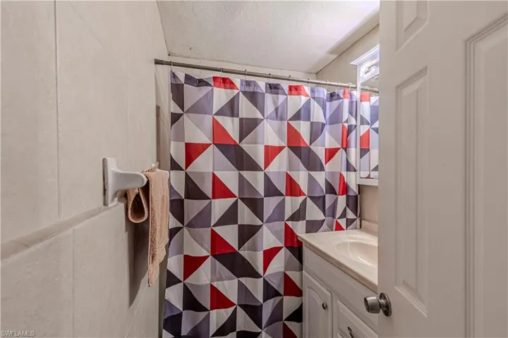 Unit A)Bathroom featuring a shower with shower curtain, vanity, a textured ceiling, and tile walls