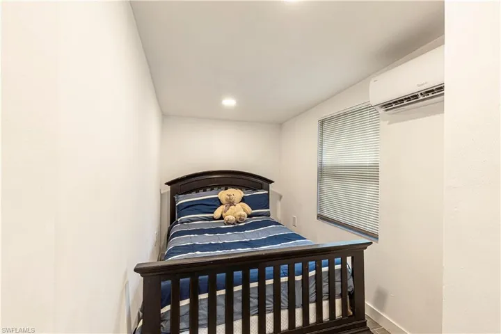 Unit C)Bedroom with a wall mounted AC and recessed lighting
