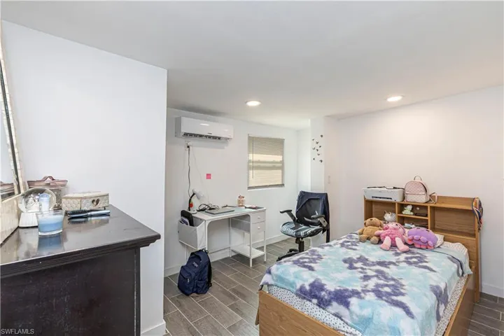 Unit C)Bedroom featuring wood finish floors, recessed lighting, and a wall mounted AC