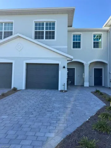 View of front of property with stucco siding, driveway, and an attached garage