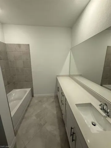 Full bath featuring double vanity and baseboards