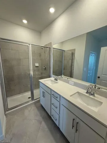 Full bathroom with a stall shower, double vanity, and light tile patterned flooring