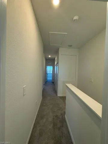Corridor with dark carpet, recessed lighting, and an upstairs landing