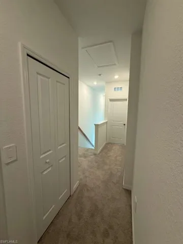 Hall with an upstairs landing, carpet floors, and a textured wall