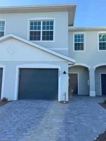 View of front of property with stucco siding, driveway, and an attached garage