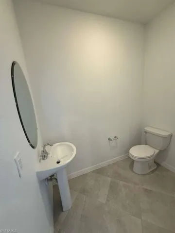 Half bathroom with toilet and baseboards