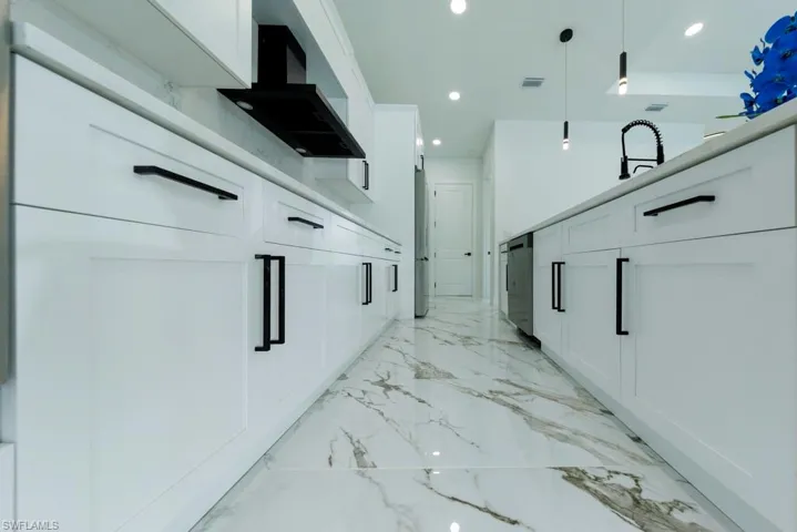 Hallway with recessed lighting, light marble finish floors, and a sink