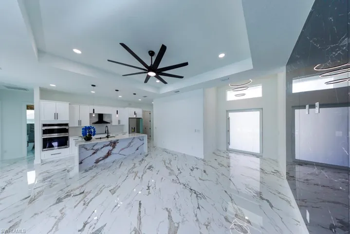 Unfurnished living room with a tray ceiling, a sink, healthy amount of natural light, recessed lighting, and a ceiling fan