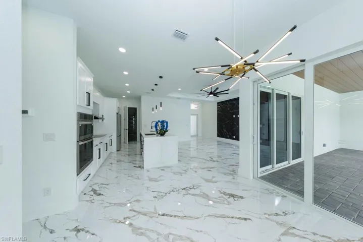 Unfurnished living room featuring a chandelier, recessed lighting, and light marble finish floors