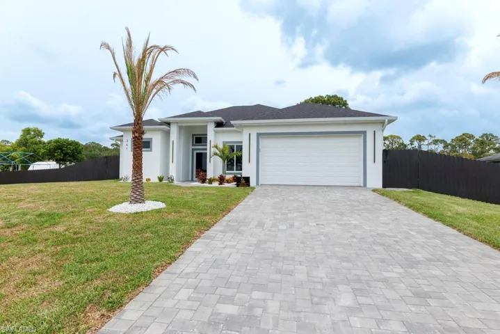 View of front facade with decorative driveway, stucco siding, and an attached garage