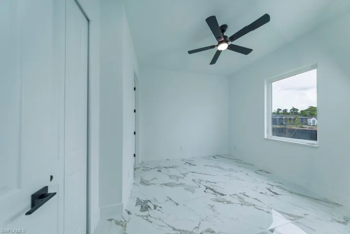 Unfurnished bedroom featuring baseboards, marble look tiles, and ceiling fan
