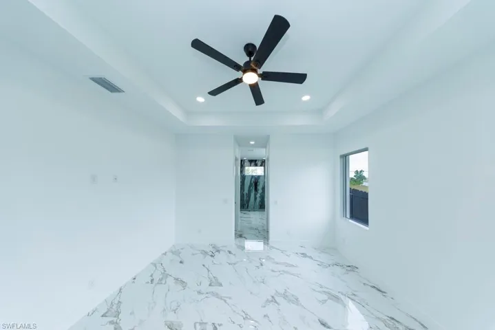 Empty room with recessed lighting, marble finish floors, baseboards, a tray ceiling, and ceiling fan
