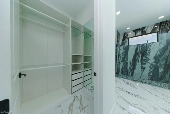 Walk in closet featuring marble finish floors