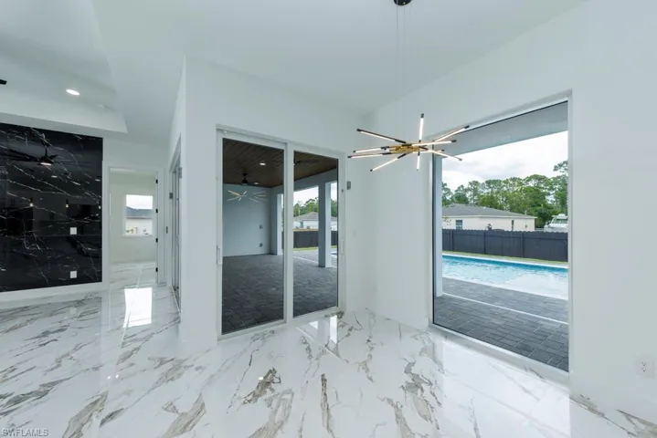 Unfurnished room with healthy amount of natural light, a chandelier, recessed lighting, and marble tiled floors