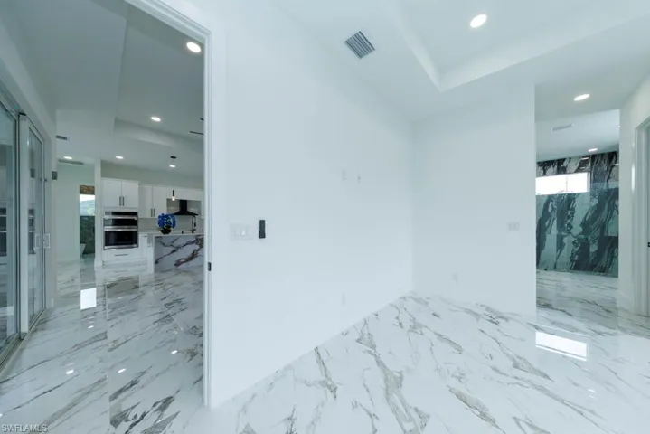 Spare room with recessed lighting, light marble finish flooring, baseboards, and a raised ceiling