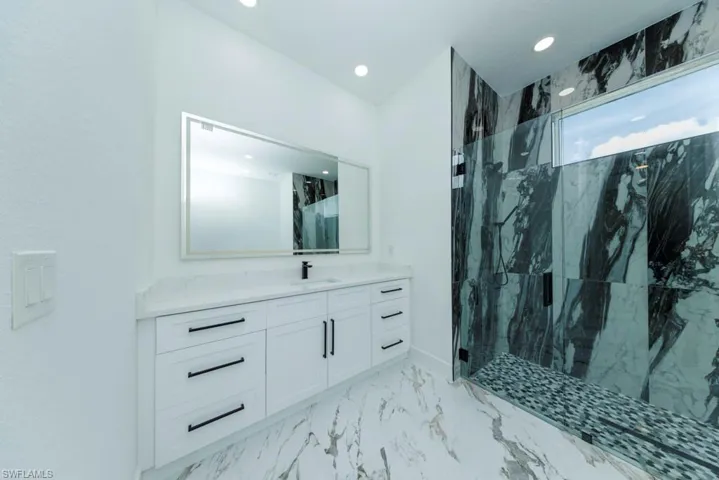 Full bath featuring a marble finish shower, vanity, recessed lighting, and marble finish floors
