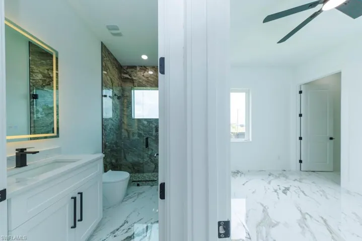 Bathroom featuring marble finish floors, a marble finish shower, vanity, and toilet
