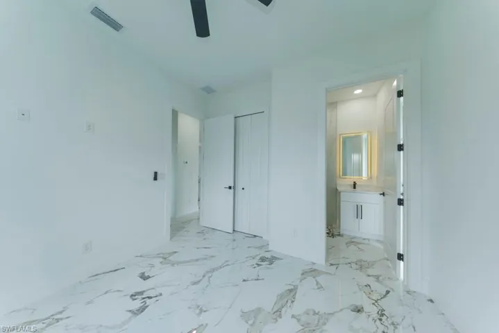 Unfurnished bedroom with baseboards, light marble finish flooring, ensuite bathroom, a closet, and recessed lighting