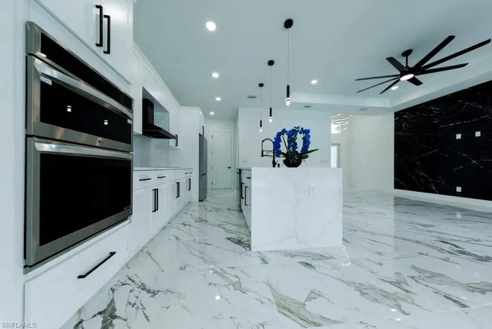 Kitchen featuring wall chimney exhaust hood, appliances with stainless steel finishes, white cabinets, recessed lighting, and ceiling fan