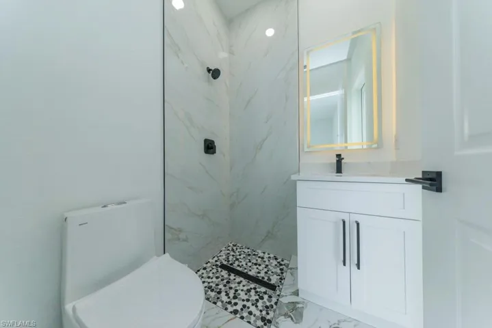 Full bathroom with marble finish flooring, a marble finish shower, vanity, and toilet