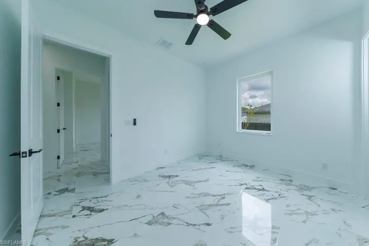 Empty room with a ceiling fan, baseboards, and light marble finish flooring