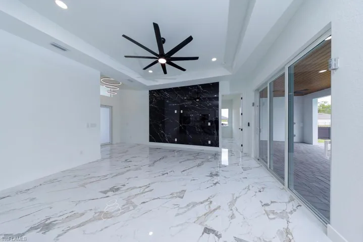 Unfurnished living room with recessed lighting, ceiling fan, and a raised ceiling