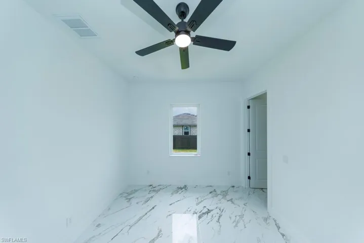 Unfurnished room with baseboards, light marble finish flooring, and a ceiling fan