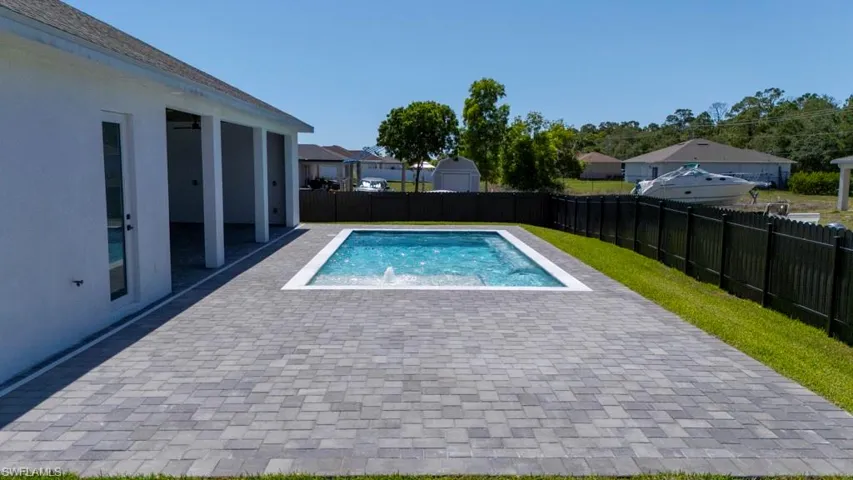 View of swimming pool with a fenced backyard, a patio area, a hot tub, and a residential view