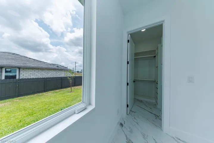 Corridor with marble look tile flooring and baseboards