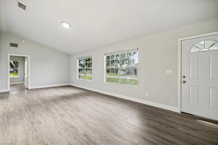 Entrance foyer featuring dark hardwood / wood-style floors, vaulted ceiling, and a healthy amount of sunlight
