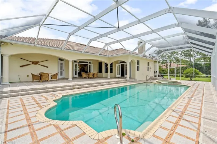 View of swimming pool featuring a ceiling fan, a patio, a pool with connected hot tub, outdoor dining area, and a lanai