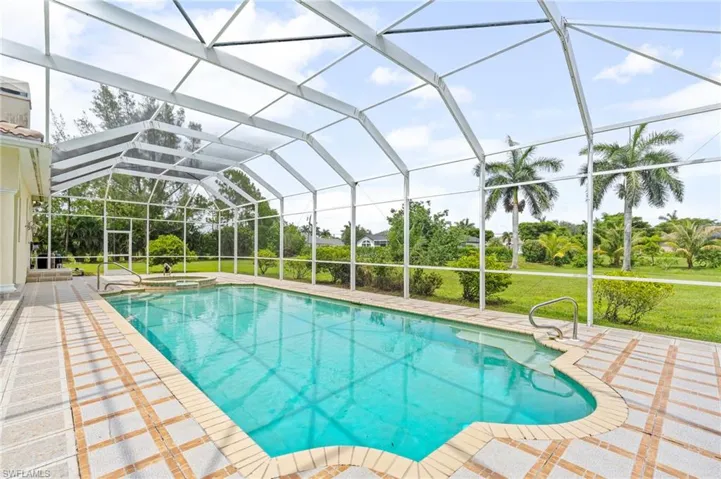 View of pool featuring a pool with connected hot tub, a patio, a lanai, and a yard