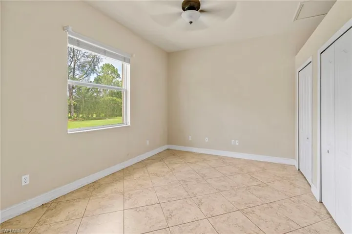 Unfurnished bedroom with two closets, light tile patterned floors, and a ceiling fan