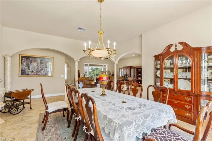 Dining space featuring arched walkways, decorative columns, light tile patterned flooring, and a chandelier