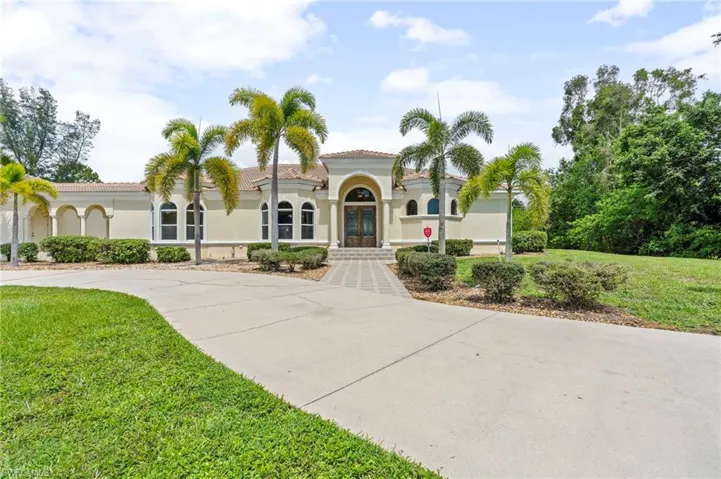 Mediterranean / spanish house featuring french doors, a front yard, driveway, stucco siding, and a tiled roof