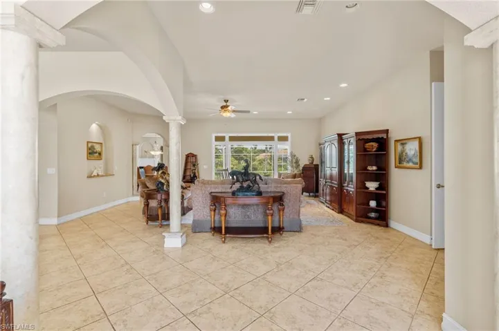 Living room featuring decorative columns, light tile patterned floors, ceiling fan, recessed lighting, and arched walkways