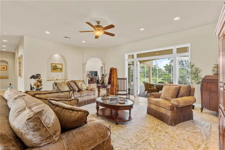 Living room with arched walkways, ceiling fan, and recessed lighting