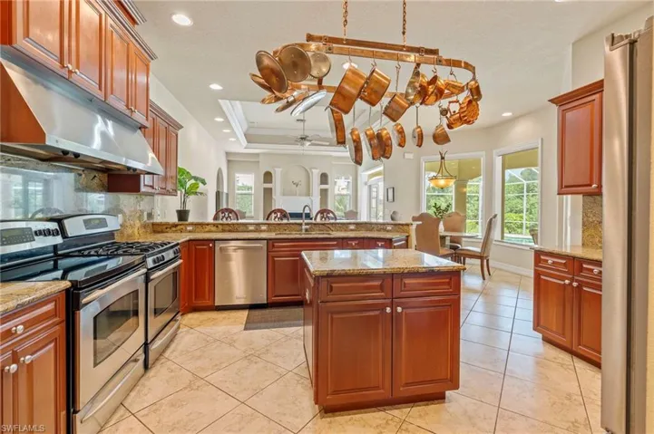 Kitchen featuring stainless steel appliances, a peninsula, under cabinet range hood, backsplash, and ceiling fan