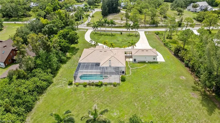 Aerial view of property and surrounding area featuring a pool area and a tree filled landscape