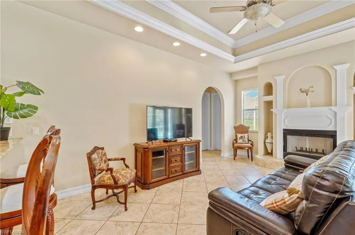 Living area with ornamental molding, a ceiling fan, recessed lighting, arched walkways, and a towering ceiling