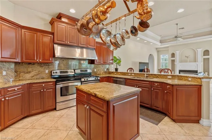 Kitchen featuring appliances with stainless steel finishes, under cabinet range hood, a peninsula, a ceiling fan, and tasteful backsplash